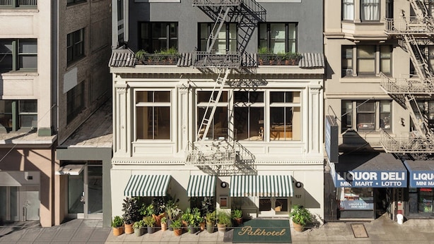 A multi-story building with a fire escape, a ground-level entrance with a sign reading "Patio Hotel," and a storefront with a sign for "Liquor Deli."