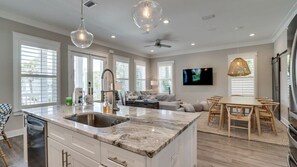 Una cocina moderna con una isla grande, electrodomésticos integrados y un comedor con mesa y sillas de madera.