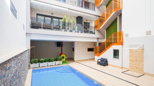 Une piscine intérieure à plusieurs niveaux, dotée d’un bassin aux eaux d’un bleu cristallin, et dont l’intérieur est décoré dans des tons de blanc et de vert.