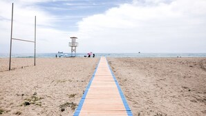 Une plage avec une promenade en bois menant à un poste de surveillance des sauveteurs.
