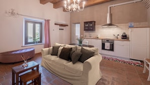 A cozy living room with a sofa, a wooden table, and a chandelier. - Apartment in Noble Villa Near Ecological Park (Mombaroccio)