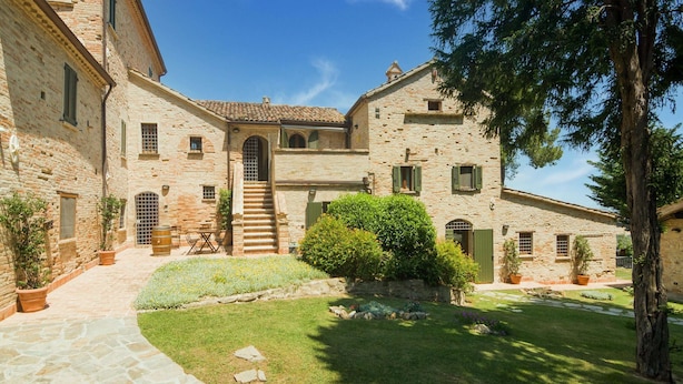 A stone building with a courtyard, a staircase leading to the entrance, and potted plants. - Apartment in Noble Villa Near Ecological Park (Mombaroccio)