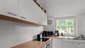A modern kitchen with white cabinets, a wooden countertop, a built-in oven, a microwave, and a coffee maker. - Home in Steinbach-hallenberg (Steinbach-Hallenberg)