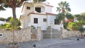Una casa de dos pisos con un muro de piedra y una reja de metal.