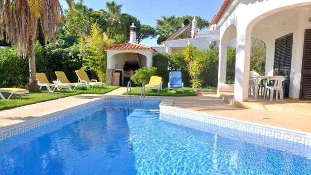 Una piscina con sillas de descanso y un patio cubierto.
