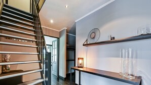 A modern staircase with a metal railing, a wall-mounted shelf with decorative items, and a small table with a candle. - Tasteful Villa in Didam With Garden (Didam)