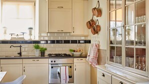 Een keuken met een fornuis, oven, kastjes en een raam met plantenpotten.