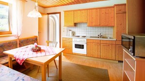 A cozy kitchen with wooden cabinets, a dining table with a checkered tablecloth, and a hanging light fixture.