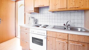 A kitchen with wooden cabinets, a white countertop, a stove, a sink, and a coffee maker.