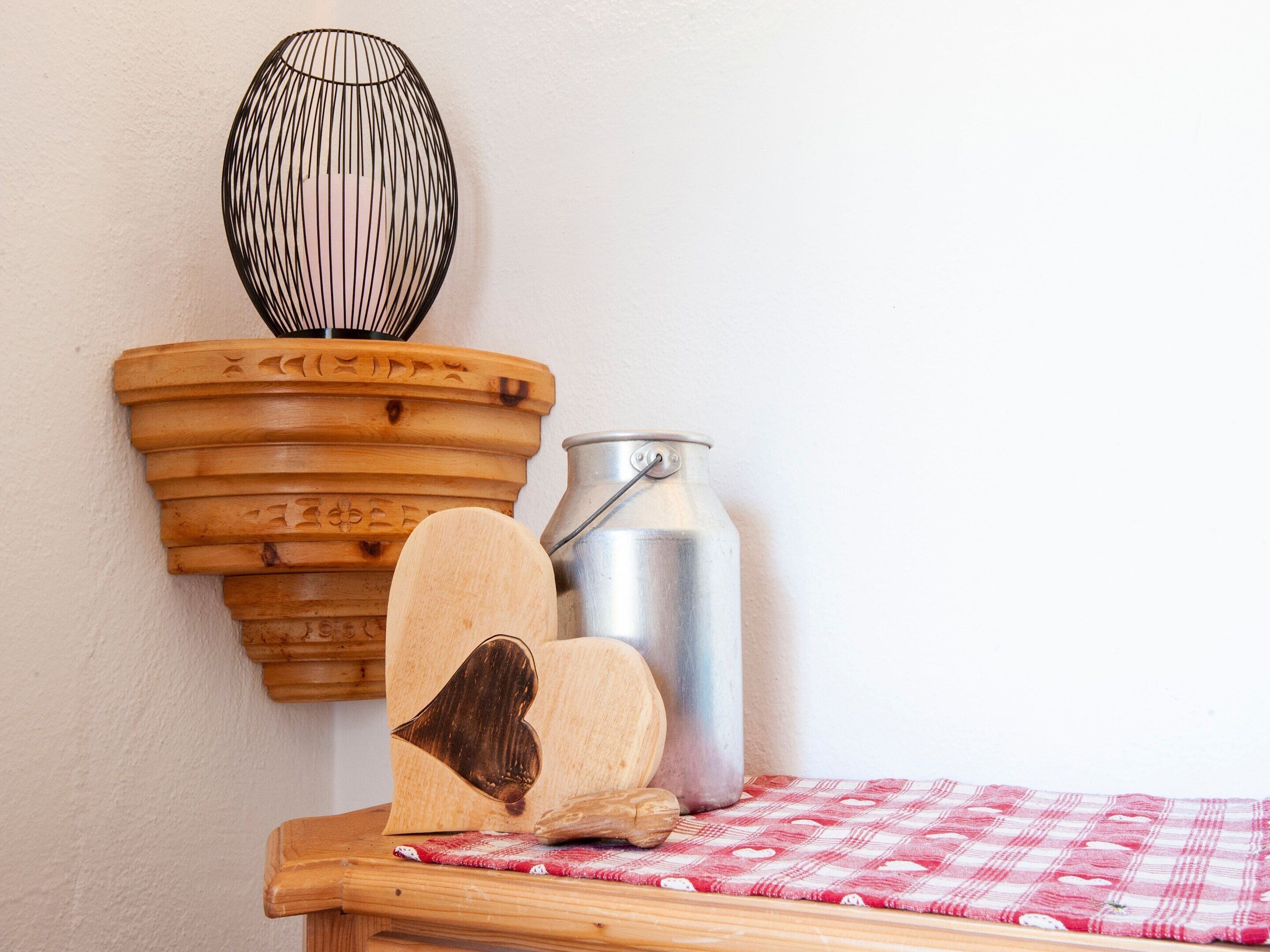 Ein Holzregal mit einem Metallbehälter und einem herzförmigen Holzgegenstand.