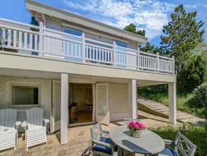 A two-story house with a balcony, a patio with chairs and a table, and a covered entryway. - Serene Apartment in Noordwijk Near Northsea (Noordwijk)
