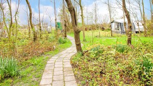 A paved garden path surrounded by trees and greenery.