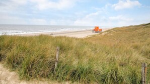 A beach with a dune system, a wooden fence, and an orange lifeguard tower.
