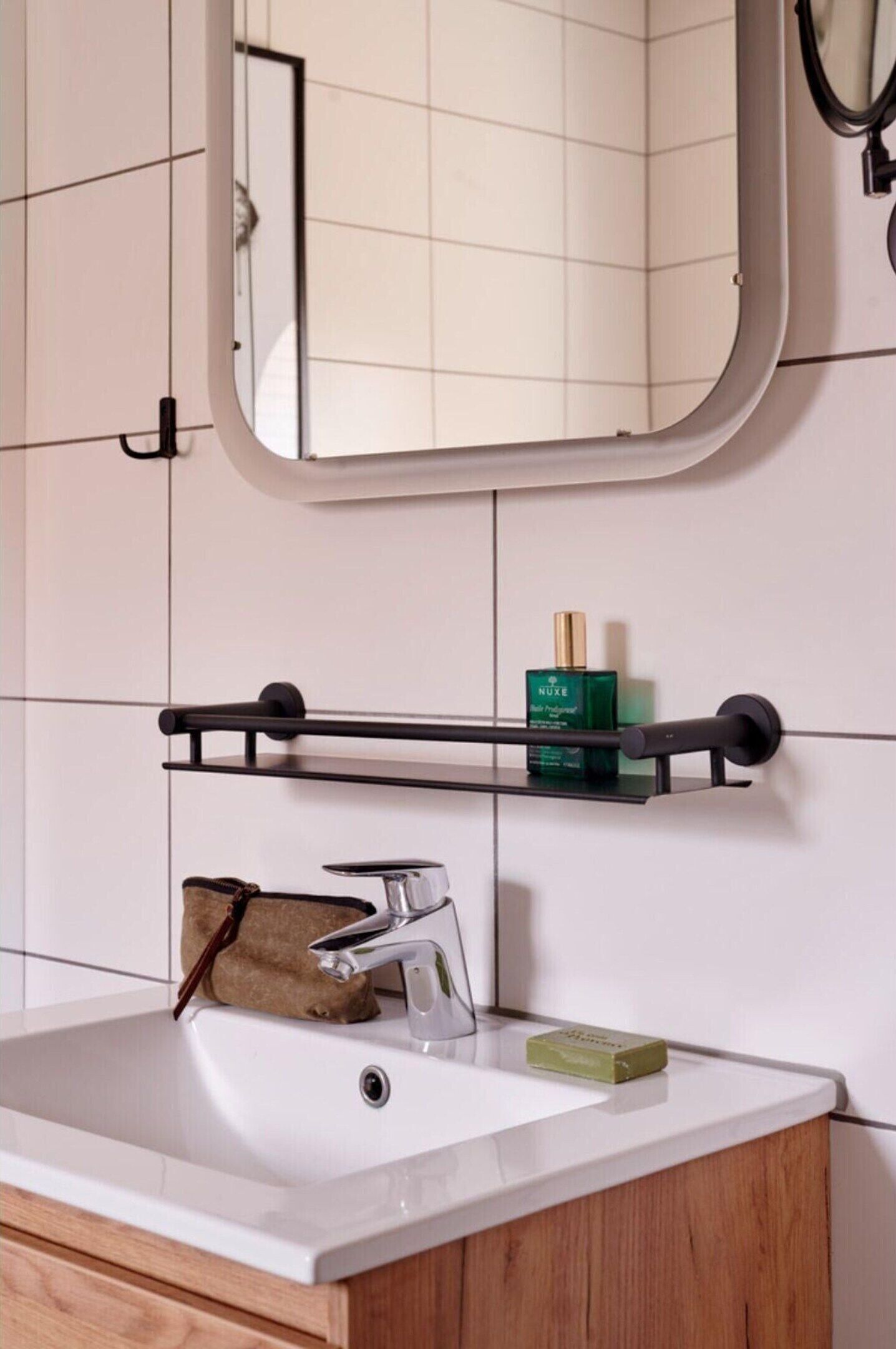 Een badkamer met een witte wastafel, een spiegel en een handdoekhouder.