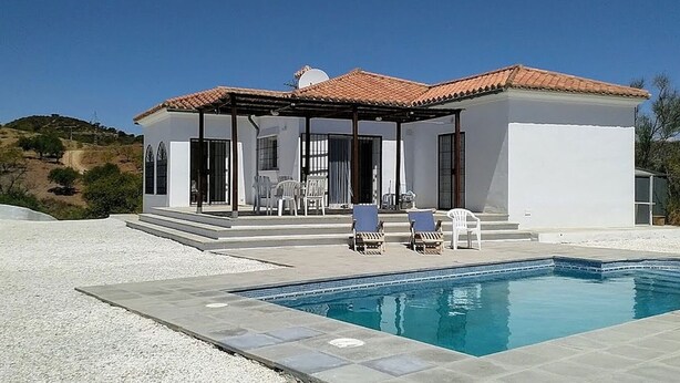 Una casa moderna con piscina, mobiliario exterior y una vista despejada del paisaje circundante.