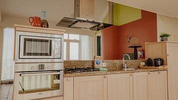 A kitchen with a Bosch oven, a gas stove, wooden cabinets, a sink, and a window with curtains.