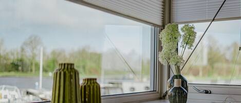 A window with three green vases and a blue vase with white flowers on a ledge.