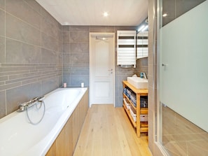 A modern bathroom with a large bathtub, a wooden vanity, and a tiled shower area. - Charming Holiday Home in Stavelot With a Garden (Stavelot)