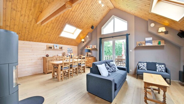 A spacious loft with a high ceiling, wooden beams, a dining area, a sofa, and a small table. - Charming Holiday Home in Stavelot With a Garden (Stavelot)