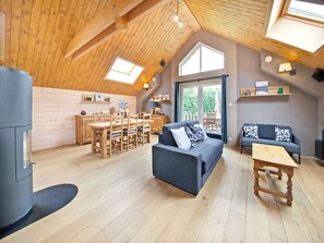 A spacious loft with a high ceiling, wooden beams, a dining area, a sofa, and a small table. - Charming Holiday Home in Stavelot With a Garden (Stavelot)