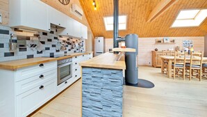 A modern kitchen with white cabinets, a stone accent wall, and a central island. - Charming Holiday Home in Stavelot With a Garden (Stavelot)