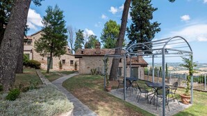 Una casa de piedra con un patio, una pérgola y vistas al campo.