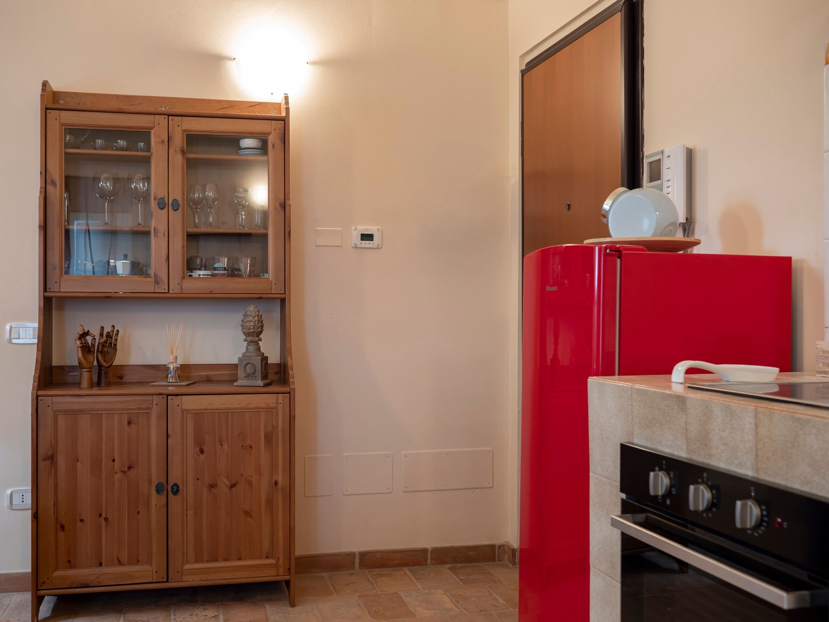 A kitchen with wooden cabinets, a red refrigerator, and a built-in oven.