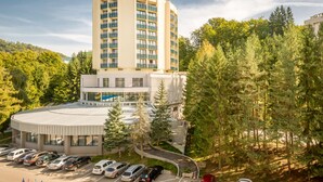 A hotel with multiple floors, a parking lot, and a forested area. - Ensana Sovata (Sovata)