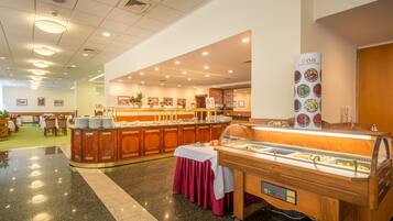 Montaje tipo bufé con varias estaciones de comida, una zona de recepción y un interior limpio y bien iluminado.