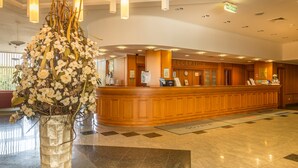A reception area with a wooden counter, a reception desk, and a large floral arrangement. - Ensana Sovata (Sovata)