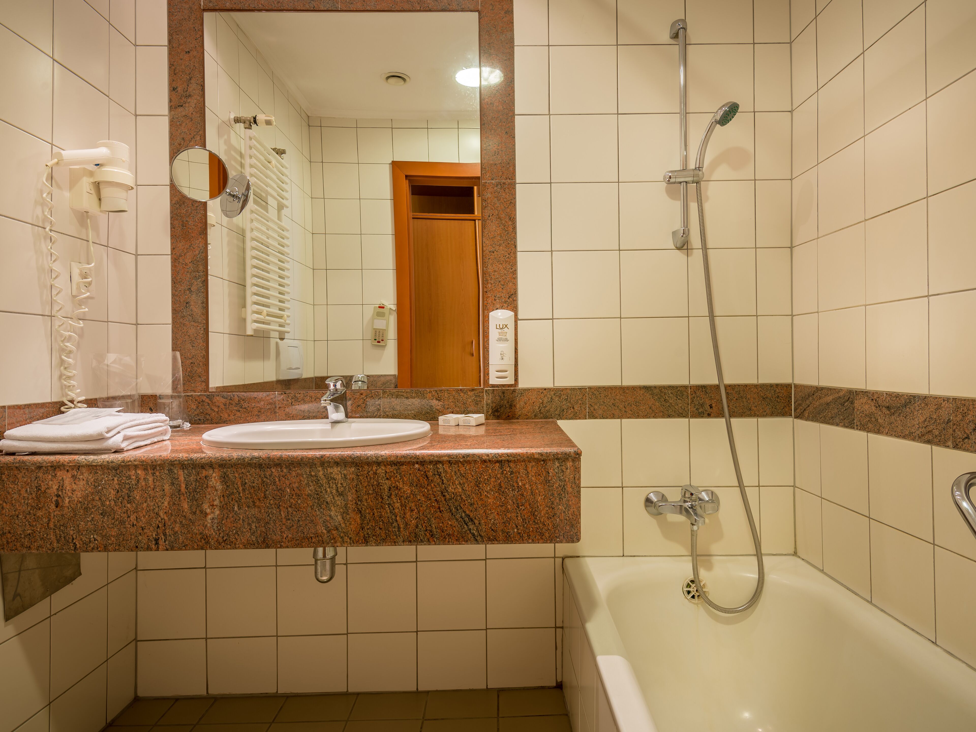 A bathroom with a sink, mirror, towel rack, and a shower.