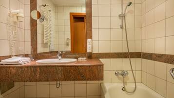 A bathroom with a sink, mirror, towel rack, and a shower.