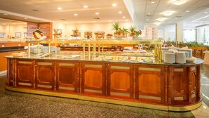 A buffet area with a wooden counter, multiple food stations, and decorative plants. - Ensana Sovata (Sovata)