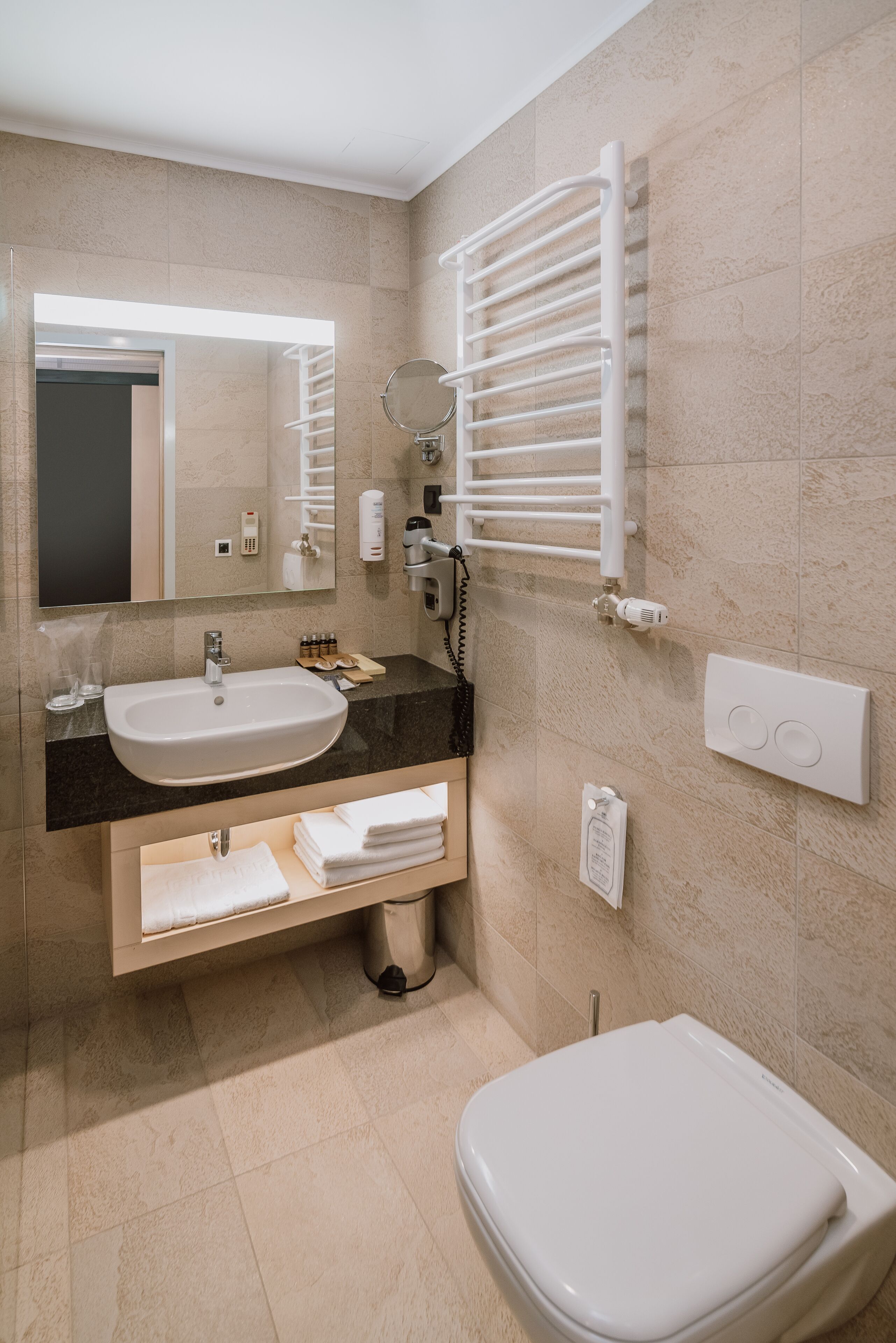 Un baño moderno con lavamanos, espejo, toallero y retrete.