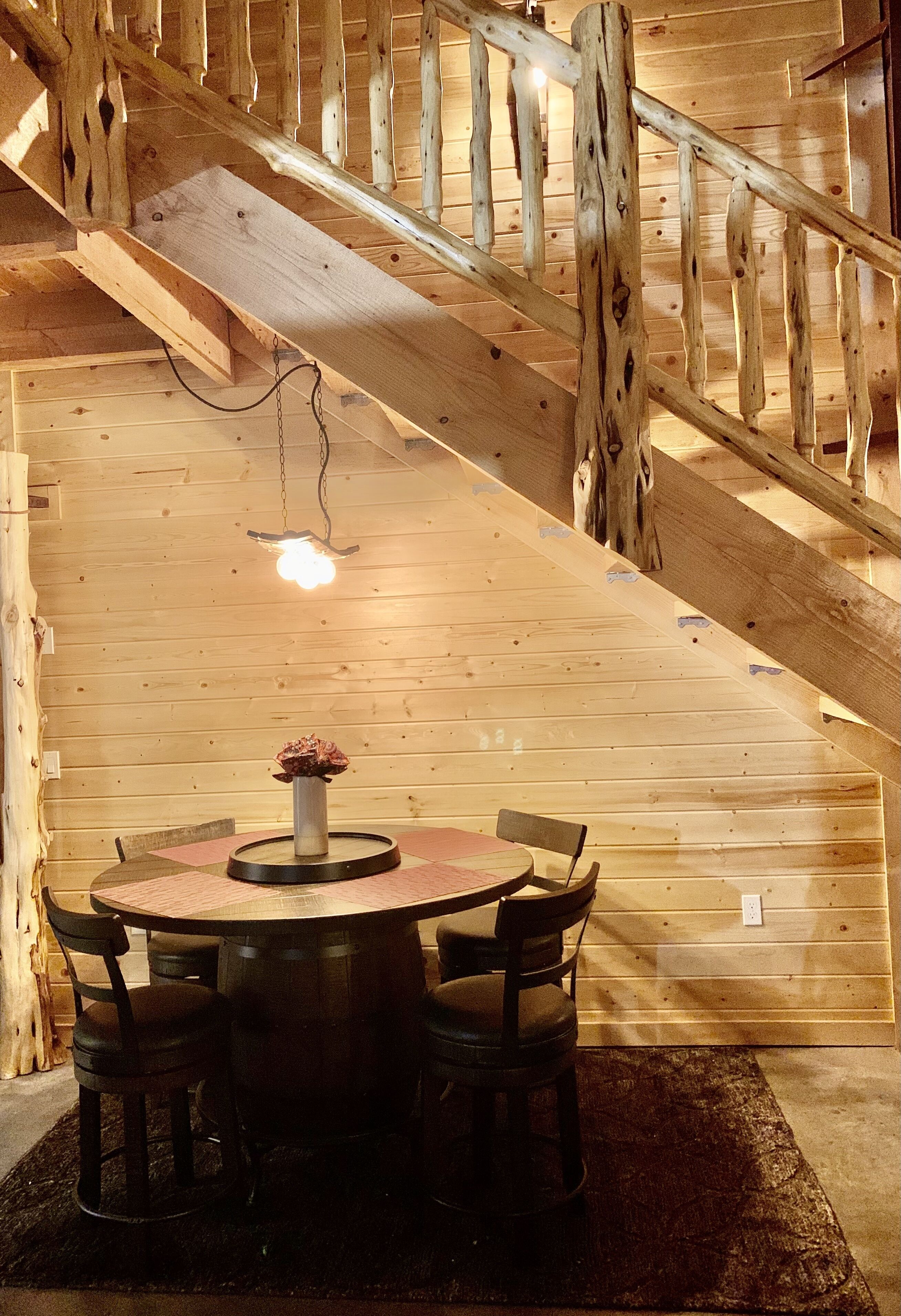 A wooden staircase with a table and chairs in a cabin.