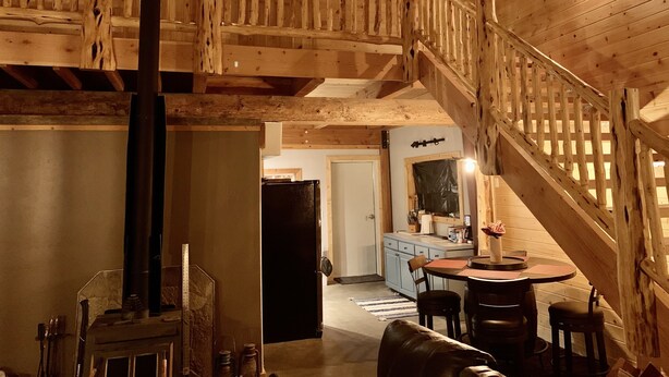 Un interior de madera con una escalera, un comedor y una cocina.