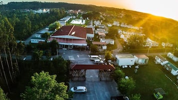 An aerial view of a residential area with houses, a large building with a red roof, and a parking lot.