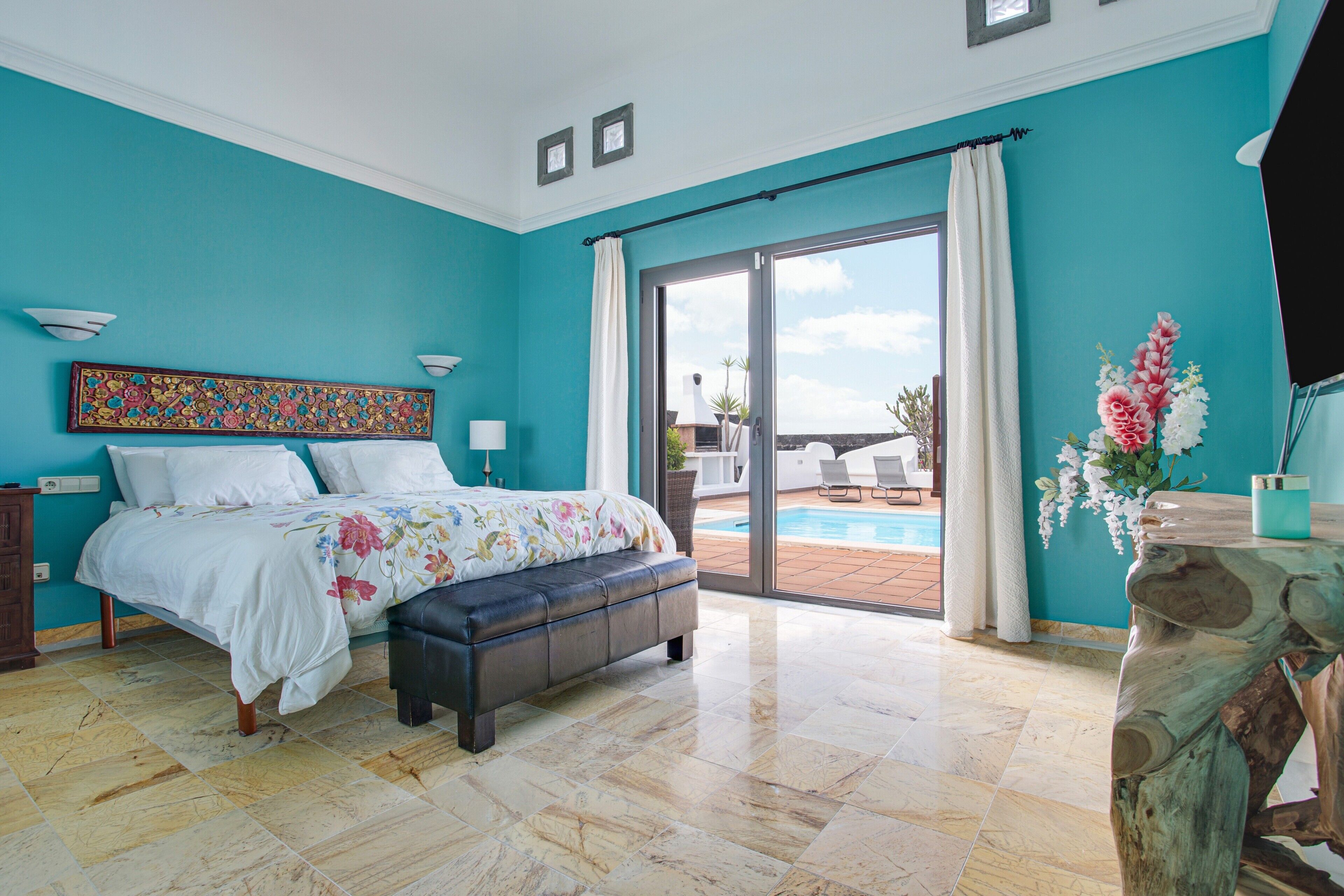 Un dormitorio con cama, una banca, un ventanal y vistas al exterior.