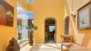 A sunlit interior with a wooden bench, a large vase, and a framed picture on the wall. - Holiday Villa Capricho with Sea & Mountain View & Pool (Lanzarote)