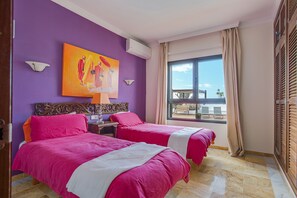 A hotel room with two beds, a large window with a view, a painting on the wall, and a balcony outside. - Holiday Villa Capricho with Sea & Mountain View & Pool (Lanzarote)