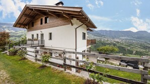 Eine zweistöckige Chalet mit Balkon, Holzgeländern und Blick auf eine Berglandschaft.