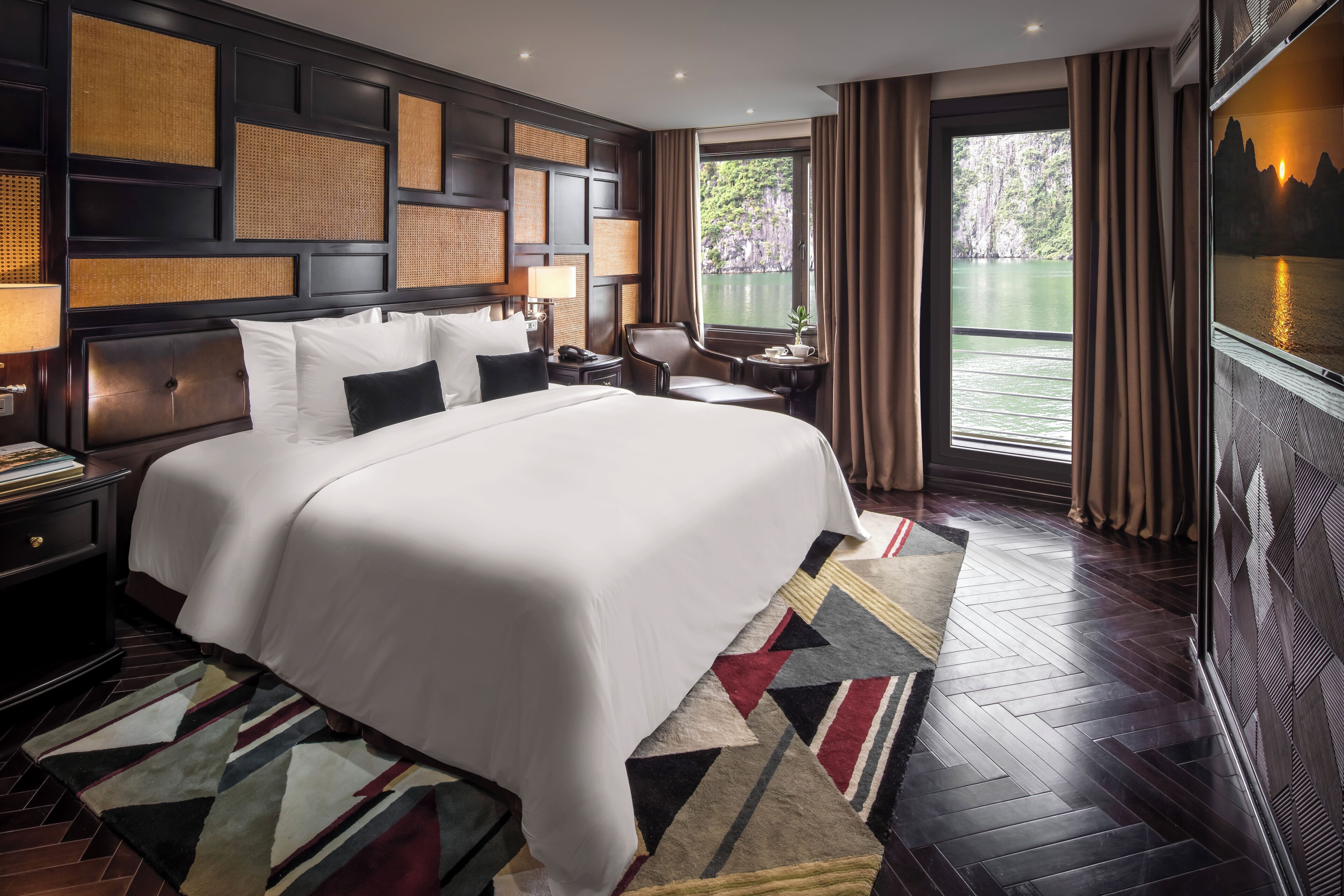 A hotel room with a large bed, a view of the water, and a TV on the wall.
