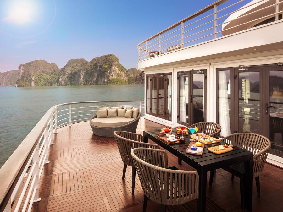 A dining area with a table, chairs, and a view of the sea and mountains.