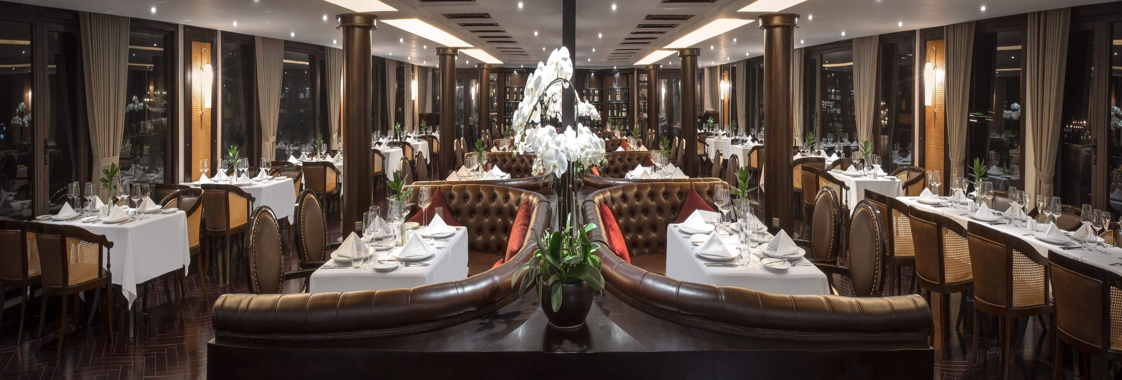 Un comedor formal con una larga mesa central, varios arreglos de asientos y una araña.