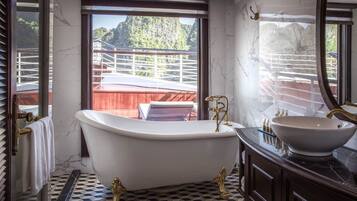 A bathroom with a freestanding bathtub, a large mirror, and a view of a balcony with a railing.