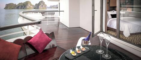 A modern suite with a balcony overlooking water and rock formations.