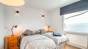 A bedroom with two beds, wooden nightstands, bedside lamps, a window with a view, and a radiator. - Holiday Home in HUY Near Town Center (Wanze)