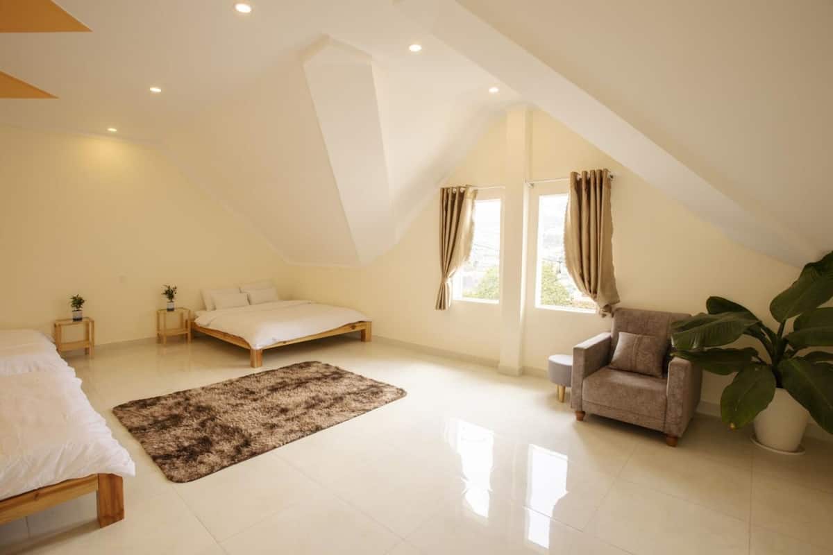 A spacious bedroom with a large bed, a smaller bed, a sofa, and a potted plant.