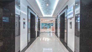 A modern hallway with a glass wall at the end, leading to a seating area. - 8rooms@ Grand Kamala Lagoon (Bekasi)