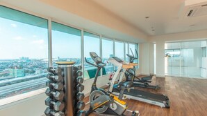 A spacious gym with cardio machines, dumbbells, and a treadmill. - 8rooms@ Grand Kamala Lagoon (Bekasi)